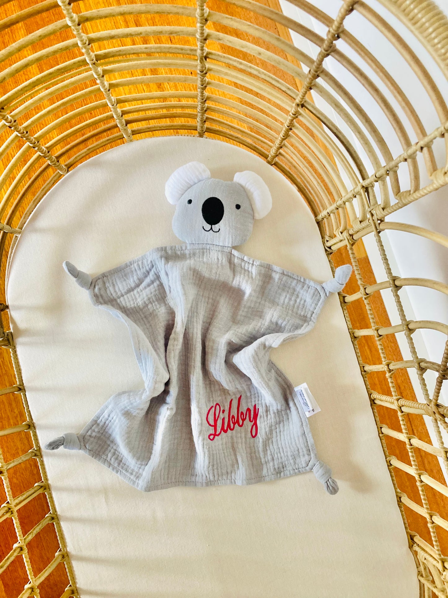 Organic muslin grey koala baby comforter in a cot, personalised with baby name Libby in pink thread. 