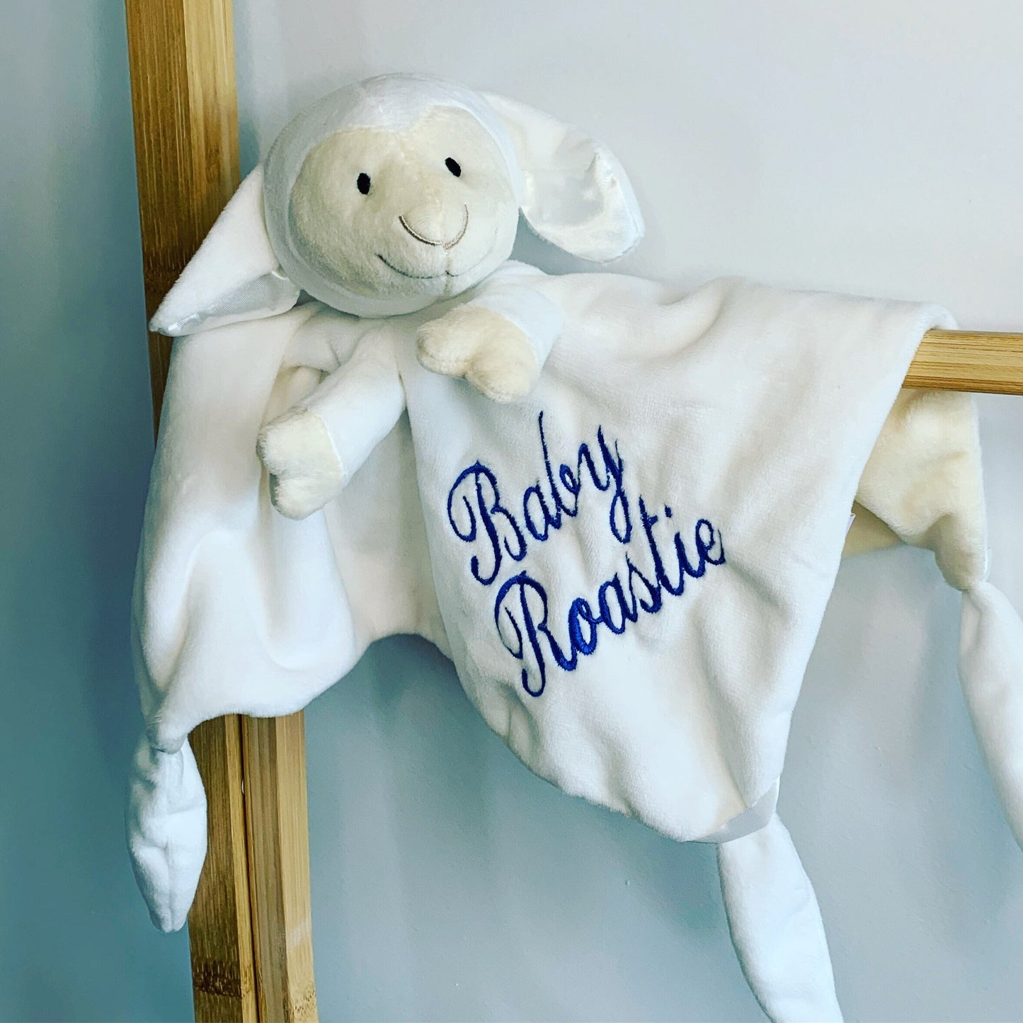 Lamb baby comforter, personalised with baby's name, embroidered using a blue thread color.